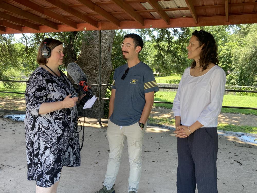 Close photograph of three people stand in Parque Zaragoza's historic bandstand. One person is wearing headphones and holding a microphone.